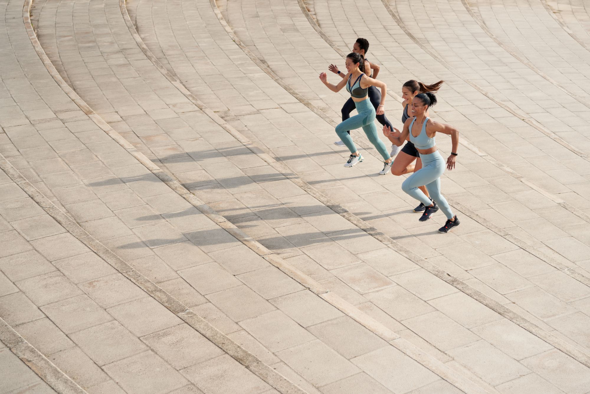 Four runners training together on a paved track